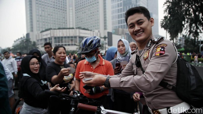 Petugas dari Polantas Polda Metro Jaya memberikan sosialisasi Berkendara Dengan Aman di kawasan Car Free Day, Bundara HI, Jakarta Pusat, Minggu (3/7). Kegiatan ini bertujuan memberikan edukasi kepada warga tentang kampanye aman  berkendara.
