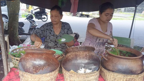 Ni Komang Dana dan menantunya Ni Luh Putu Widhiastuti saat menyajikan bubur sumsum kepada para pelanggan di Pasar Senggol Bebandem, Karangasem, Minggu (3/7/2022).