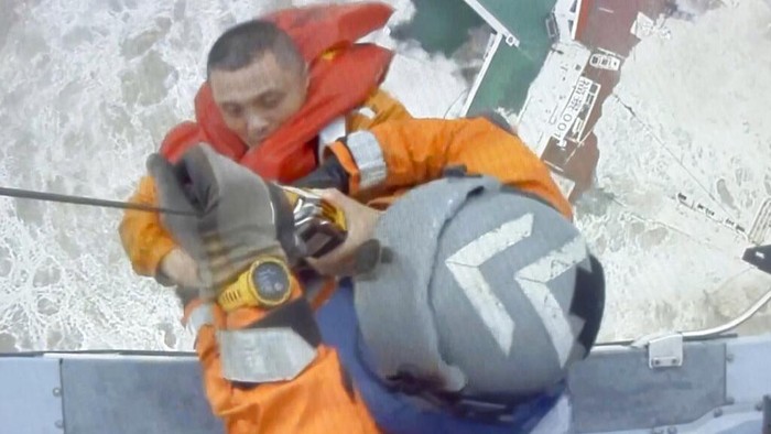 In this image released by Hong Kong Government Flying Service, helicopter crew members winch up a man from a sinking ship in the South China Sea, 300 kilometers (186 miles) south of Hong Kong, Saturday, July 2, 2022, as Typhoon Chaba was moving in the area. The industrial support ship operating in the South China Sea has sunk with the possible loss of more than two dozen crew members, rescue services in Hong Kong said Saturday. (Hong Kong Government Flying Service via AP)