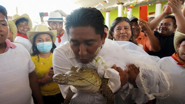 The San Pedro Huamelula Mayor Victor Hugo Sosa kisses a seven-year-old alligator dressed as a bride during a traditional ritual marriage, likely dates back centuries to pre-Hispanic times, between the mayor and the reptile that depicts a princess, as a prayer to plead for natures bounty, in San Pedro Huamelula, in Oaxaca state, Mexico June 30, 2022. REUTERS/Jose de Jesus Cortes     TPX IMAGES OF THE DAY