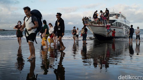 Para penumpang naik dan turun kapal langsung di bibir Pantai Sanur, Bali, Sabtu (2/7/2022). Pemandangan ini terlihat karena pelabuhan masih dalam proses pembangunan. Pelabuhan Sanur diperkirakan selesai pada September 2022.