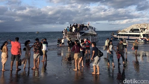 Para penumpang naik dan turun kapal langsung di bibir Pantai Sanur, Bali, Sabtu (2/7/2022). Pemandangan ini terlihat karena pelabuhan masih dalam proses pembangunan. Pelabuhan Sanur diperkirakan selesai pada September 2022.