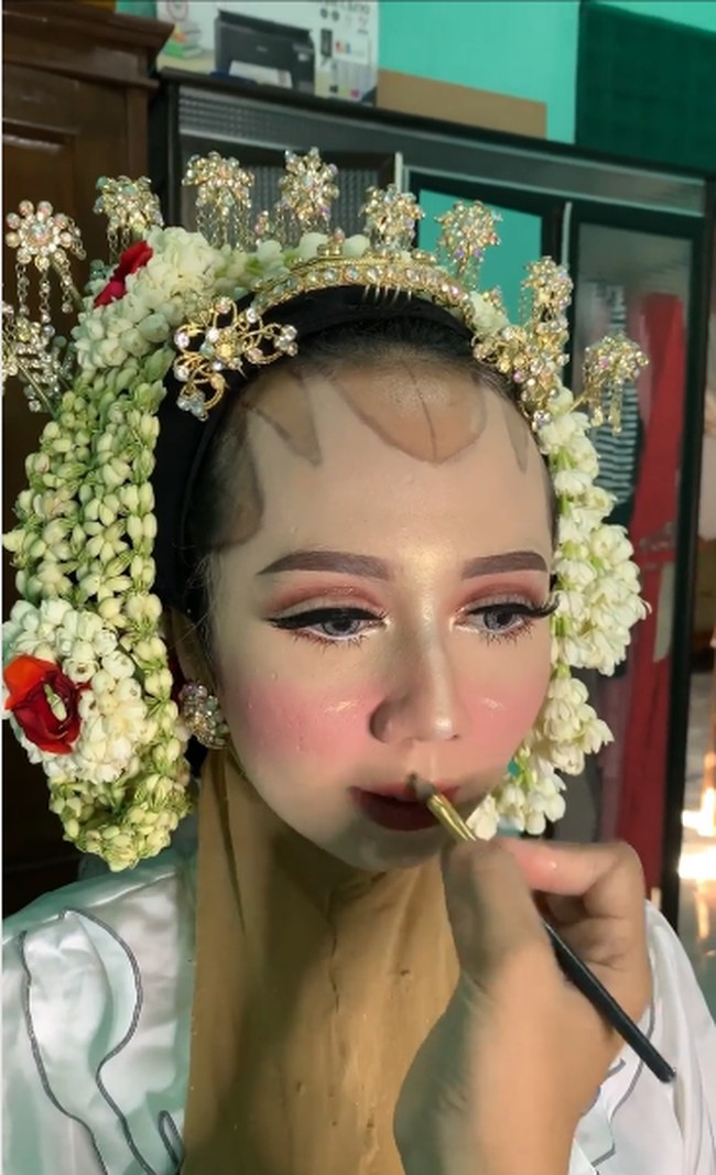 Pengantin wanita yang memakai kebaya hijau dan roncean melati itu terlihat manglingi setelah dirias. Noda bekas cacar di wajahnya pun tersamarkan. Ia terlihat senang dan bahagia melihat hasil makeup. Video unggahan Elin yang memperlihatkan transformasi makeup pengantin dengan bekas cacar itu sudah ditonton lebih dari 108 ribu Views. Riasannya mendapatkan banjir pujian karena pengantin tampil flawless dan cantik. Foto: Dok. Instagram @elinnherlin_.
