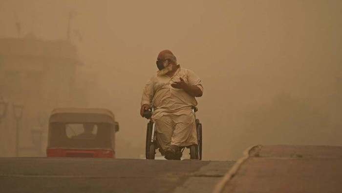 A man navigates his wheelchair on a street during a sandstorm in Baghdad, Iraq, Sunday, July 3, 2022. (AP Photo/Hadi Mizban)
