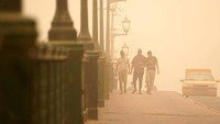 Orang-orang berjalan di jembatan saat badai pasir di Baghdad, Irak, Minggu, (3/7/2022).
