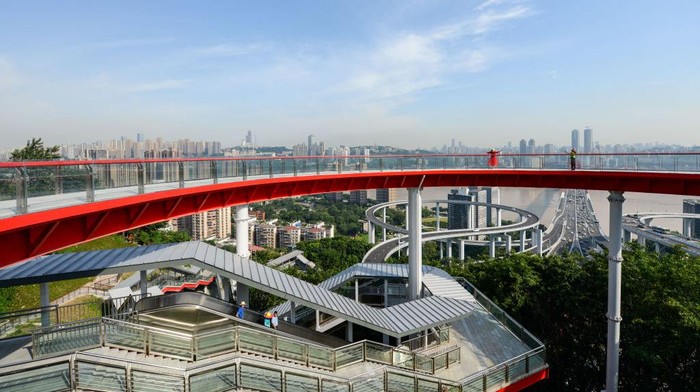 1406199508 CHONGQING, CHINA - JUNE 30: A visitor poses for photos at Sujiaba trail observation deck, a circular viewing platform, on June 30, 2022 in Chongqing, China. The deck opened to the public on Thursday, offering a unique perspective of the booming megacity in southwestern China. It started from the Tongyuanju Station of Chongqing Rail Transit and ended at Shuangfengshan Road, reducing travel time in the city built on mountains. (Photo by He Penglei/China News Service via Getty Images)