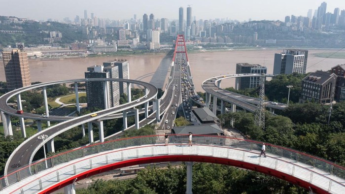 1406199508 CHONGQING, CHINA - JUNE 30: A visitor poses for photos at Sujiaba trail observation deck, a circular viewing platform, on June 30, 2022 in Chongqing, China. The deck opened to the public on Thursday, offering a unique perspective of the booming megacity in southwestern China. It started from the Tongyuanju Station of Chongqing Rail Transit and ended at Shuangfengshan Road, reducing travel time in the city built on mountains. (Photo by He Penglei/China News Service via Getty Images)