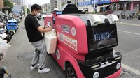 Seorang pekerja supermarket memindai kode QR untuk memesan pengantaran paket pada kendaraan pengiriman tanpa pengemudi.