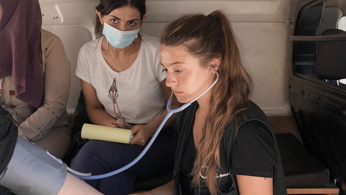 Foto Udara Kamp Pengungsi Suriah di Libanon A volunteer health worker examines a patient at a mobile clinic of