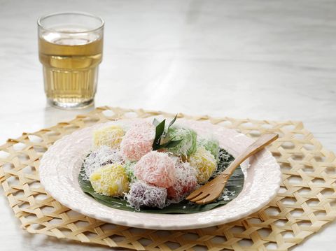 Colorful Ongol Ongol or Sentiling, Steamed Cassava Cake Coating with Grated Coconut, Served on Ceramic Plate. Copy Space for Text