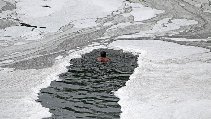 A man paddles his raft while collecting recyclable materials in the waters of river Yamuna coated with polluted foam in New Delhi on July 5, 2022. (Photo by Sajjad HUSSAIN / AFP) (Photo by SAJJAD HUSSAIN/AFP via Getty Images)