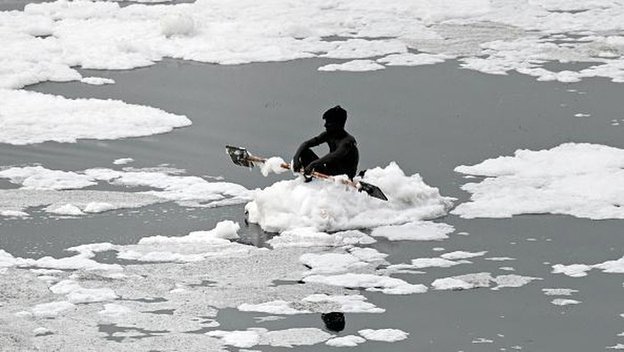 A man paddles his raft while collecting recyclable materials in the waters of river Yamuna coated with polluted foam in New Delhi on July 5, 2022. (Photo by Sajjad HUSSAIN / AFP) (Photo by SAJJAD HUSSAIN/AFP via Getty Images)