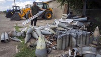 Seorang petani mengumpulkan pecahan roket Rusia yang berserakan di ladangnya yang berjarak sekitar sepuluh kilometer dari garis depan pertahanan di wilayah Dnipropetrovsk, Ukraina pada Senin (4/7/2022). (Efrem Lukatsky/AP Photo).
