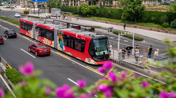 CHENGDU, CHINA - JULY 04: A red 'Shudu' train, featuring the Bashu civilization, stops at a train station on July 4, 2022 in Chengdu, Sichuan Province of China. The 30.2-meter-long smart trackless trains 'Shudu' and 'Tianfu' with a maximum capacity of 300 passengers conducted trial runs in Chengdu on Monday. The smart trackless trains have rubber tires and a small turning circle, equivalent of the turning radius of a 12-meter bus. Sichuan was known as Shu in ancient times, and Shudu means capital of Sichuan. (Photo by Liu Zhongjun/China News Service via Getty Images)