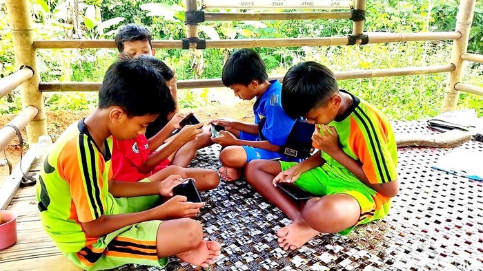 Sejumlah anak tengah berkumpul untuk mendapat akses internet gratis.