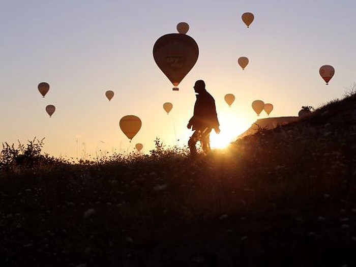 NEVSEHIR, TURKIYE - JULY 4: Hot air balloons glide over the sky at Cappadocia which attracts tourists with its historical, cultural and natural beauties in Nevsehir, Turkiye on July 4, 2022. The number of tourists flied with hot air balloons increased in the first half of this year compared to the same period last year, reaching 258,914. (Photo by Behcet Alkan/Anadolu Agency via Getty Images)