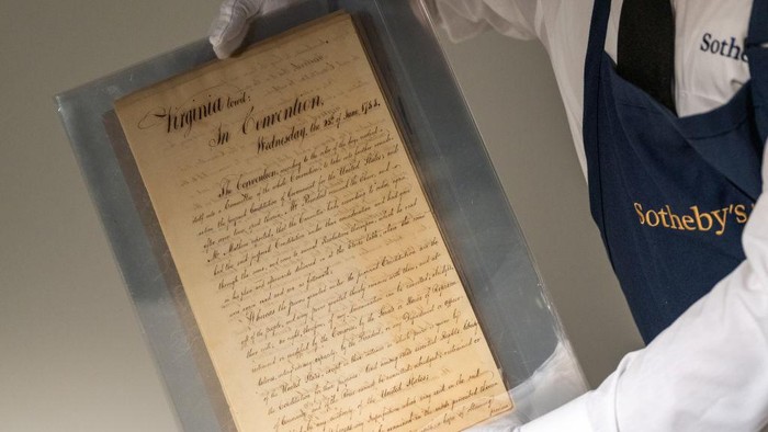 1406957691 NEW YORK, NEW YORK - JULY 05: An art handler holds a copy of Virginia’s Official Ratification of the United States Constitution at Sotheby's on July 05, 2022 in New York City. The text served as a precursor and direct influence on the United States Bill of Rights. It will be auctioned on July 21. (Photo by Alexi Rosenfeld/Getty Images)
