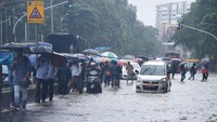 Kendaraan dan warga mengarungi jalan yang tergenang air akibat hujan lebat di S.V. Road, Mumbai, India. (Vijay Bate/Hindustan Times/Getty Images)