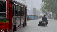 Pesepeda melewati bus yang terjebak banjir akibat hujan deras di Mumbai, India, Senin, (4/7/2022). (Indranil Aditya/NurPhoto/Getty Images)