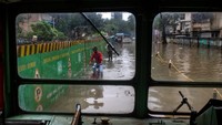 Orang-orang mengarungi jalan yang tergenang air akibat hujan lebat di S.V. Road, di Khar, Mumbai, India, Selasa, (5/7/2022). (Satish Bate/Hindustan Times/Getty Images)