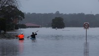 Warga lokal, James Taylor dan Joshua Myers mendayung kayak di tengah banjir di McGraths Hill, pinggiran Sydney, Australia, Rabu (6/7/2022). (Elliott/Reuters)