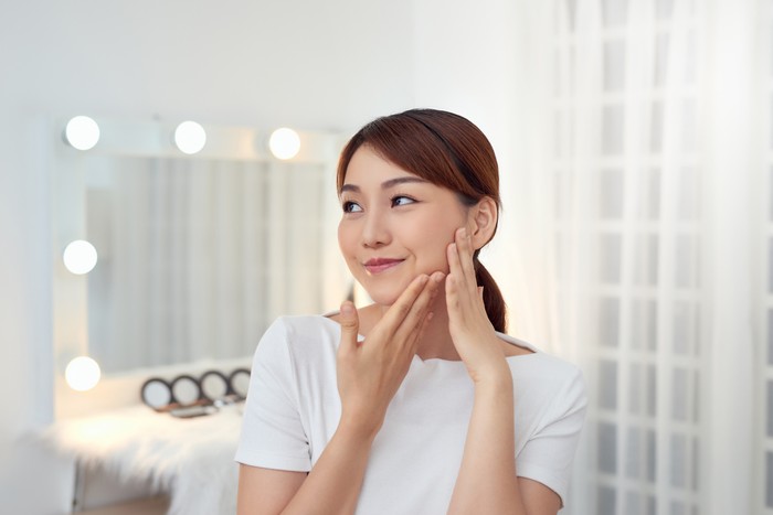 Ilustrasi Skincare Attractive young Asian girl touching her face. Beauty & Skin care concept