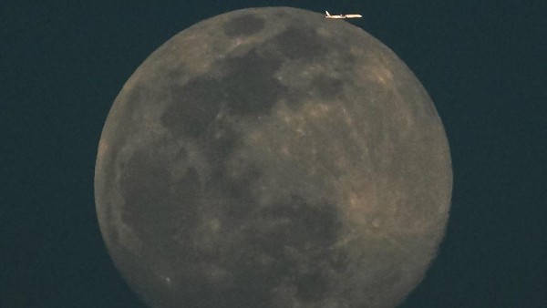 Berikutnya sebuah pesawat komersil di langit Kuwait nampak mengelilingi bulan purnama. (Yasser Al-Zayyat/AFP/Getty Images).