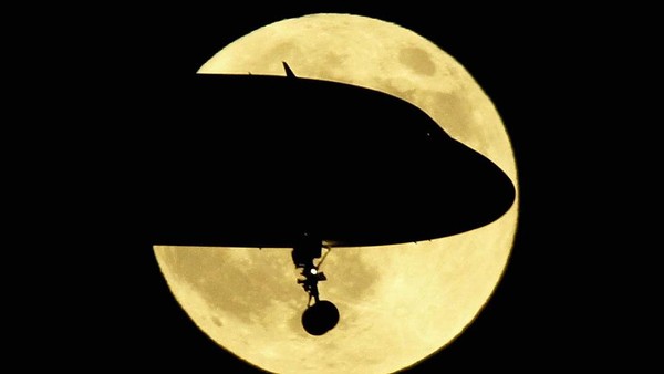 Foto ilusi optik ini membuat bulan purnama seakan terbelah oleh sebuah pesawat saat hendak mendarat di Bandara Nasional Ronald Reagan, Virginia. (Mark Wilson/Getty Images).