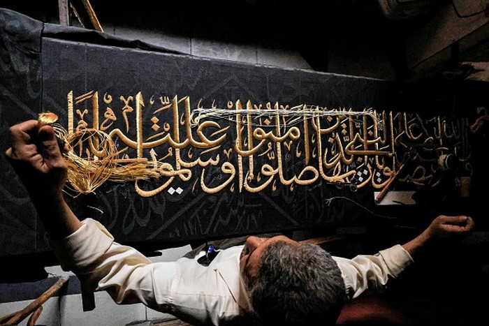An embroiderer sews with gold thread a verse from the Holy Koran, Islams holy book, onto a replica of the Kiswa, the cloth used to cover the Kaaba at the Grand Mosque in the Muslim holy city of Mecca, to be sold as a souvenir for tourists visiting the historic district of al-Hussein of Islamic Cairo in Egypts capital on June 15, 2022. - From the 13th century, Egyptian artisans made the giant cloth in sections, which authorities transported to Mecca with great ceremony. Celebrations would mark processions through cities, flanked by guards and clergymen as Egyptians sprinkled rosewater from balconies above. From 1927, manufacturing began to move to Mecca in the nascent Kingdom of Saudi Arabia, which would fully take over production of the kiswa in 1962. (Photo by Khaled DESOUKI / AFP) (Photo by KHALED DESOUKI/AFP via Getty Images)