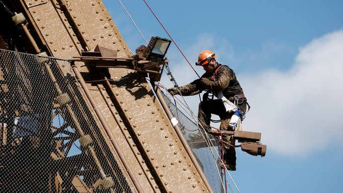 Penampakan Menara Eiffel Penuh Karat, Tapi Cuma Dicat Ulang A worker is seen on the Eiffel tower during the 20th campaign of painting and stripping of the Eiffel tower in Paris, France, July 5, 2022. REUTERS/Benoit Tessier     TPX IMAGES OF THE DAY