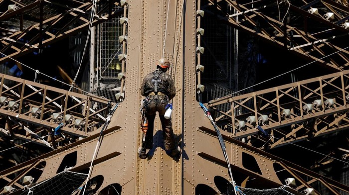 Penampakan Menara Eiffel Penuh Karat, Tapi Cuma Dicat Ulang A worker is seen on the Eiffel tower during the 20th campaign of painting and stripping of the Eiffel tower in Paris, France, July 5, 2022. REUTERS/Benoit Tessier     TPX IMAGES OF THE DAY