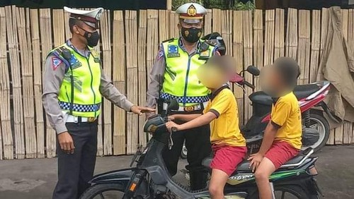 Petugas Satlantas Polres Karangasem saat menilang pengendara anak-anak di bawah umur yang melintas di jalan raya, Karangasem, Bali, Rabu (6/7/2022).