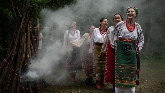 1241744281 KYIV, UKRAINE - JULY 06: Women wearing traditional Ukrainian costumes dance around the bonfire during the Ivana-Kupala celebration in Mamayeva Sloboda open air museum on July 6, 2022 in Kyiv, Ukraine. Kupala Night, also known as Ivana-Kupala, is a midsummer holiday in many slavic countries. Among the common rituals, women may float wreaths down a river to divine their romantic fortune, and couples leap hand-in-hand over bonfires in a bid for future togetherness. (Photo by Alexey Furman/Getty Images)