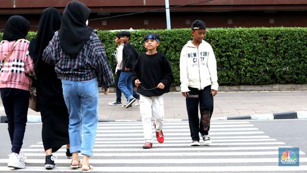 Sejumlah anak muda berjalan di kawasan Taman Sudirman, Jakarta, Kamis (7/7/2022). Tempat ini viral karena jadi ajang adu fashion anak muda yang berasal dari kawasan pinggir wilayah Jakarta seperti Citayam, Bekasi hingga Bojong Gede. (CNBC Indonesia/ Muhammad Sabki)