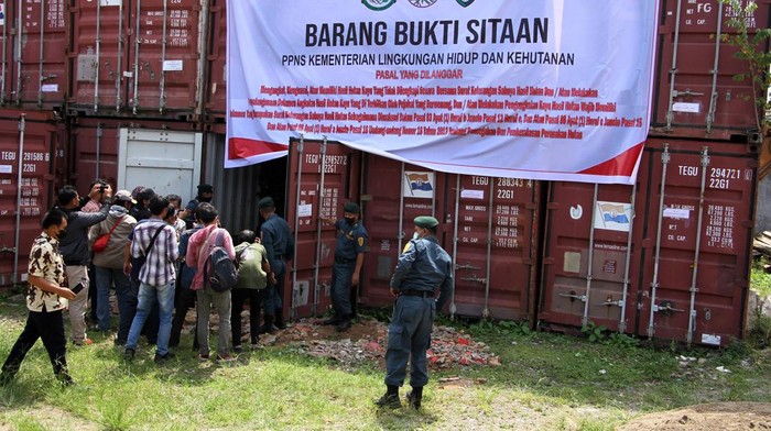 Sejumlah petugas dan wartawan berdiri di dekat kontainer yang berisi barang bukti kayu ilegal jenis Merbau asal Papua di Rumah Penyimpanan Benda Sitaan Negara (Rupbasan) Kelas I Makassar di Makassar, Sulawesi Selatan, Kamis (7/7/2022). Kementerian Lingkungan Hidup dan Kehutanan (KLHK) Wilayah Sulawesi melimpahkan dua kasus perkara kepemilikan kayu ilegal kepada Kejaksaan Negeri Makassar dengan barang bukti sebanyak 656,96 meter kubik kayu jenis Merbau dari dua tersangka yang masuk Daftar Pencarian Orang (DPO) untuk dilakukan penegakan hukum 
