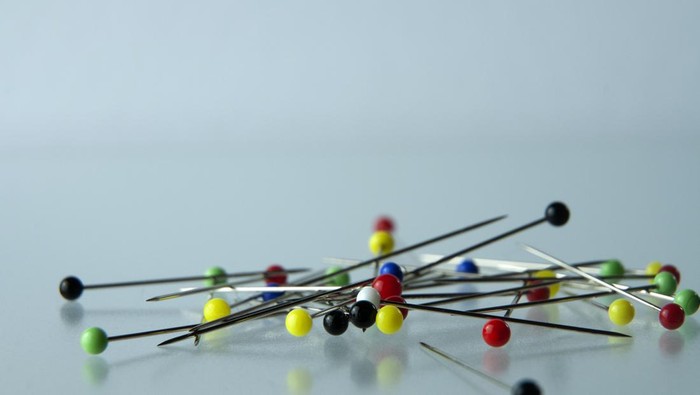 macrophotography of pins on a glass table with sphere shaped colorful glass heads