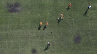 Foto udara menunjukkan anak-anak bermain sepak bola di lapangan dengan bercak hitam di beberapa titik bekas bom mortir.