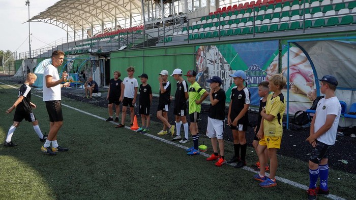Potret Anak-anak di Ukraina Main Bola di Stadion yang Dibom Rusia Young players of the Olymp football club attend a training session at the Central stadium in the Irpin town, which was heavily damaged during Russia's invasion of Ukraine, outside of Kyiv, Ukraine July 6, 2022. REUTERS/Valentyn Ogirenko