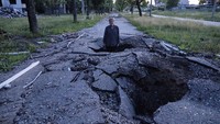 Viktor Shevchenko difoto di tengah lobang bom pada 1 Juli lalu. Invasi Rusia ke Ukraina telah memasuki bulan kelima. Invasi itu mengakibatkan kerusakan di sejumlah wilayah, salah satunya Kharkiv.