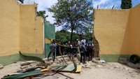 Sejumlah petugas berkumpul dekat gerbang utama penjara yang hancur usai serangan di Kuje, dekat ibu kota Abuja, Nigeria, Rabu (6/7/2022).