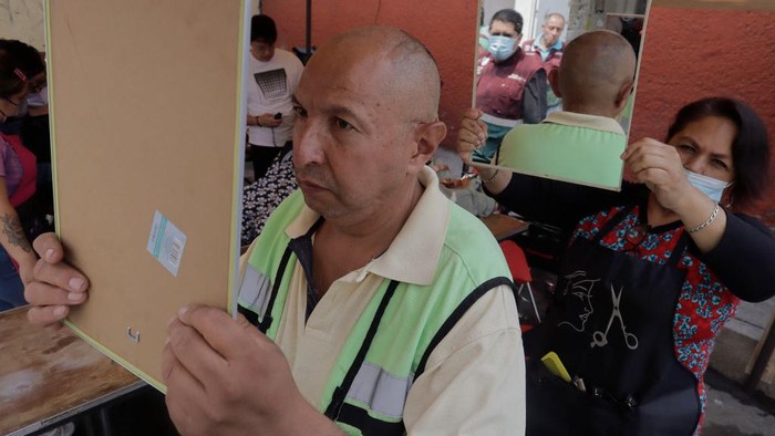 A person from Barrio San Juan del Pueblo San Francisco Culhuacán, in Mexico City, looks in the mirror after getting a free haircut as part of the activities organised by women in the area in conjunction with Mexico City authorities.

According to data from the National Institute of Statistics and Geography (INEGI), the majority of self-employed women work in the tertiary sector (81.2%) in commerce, restaurants and various services such as hairdressing, cosmetology and beauty salons. (Photo by Gerardo Vieyra/NurPhoto via Getty Images)