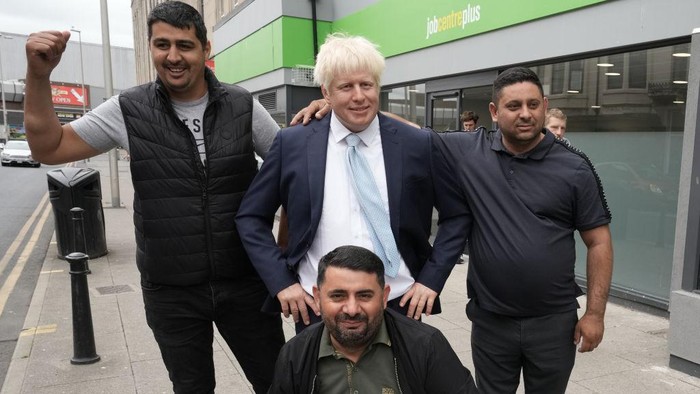 BLACKPOOL, ENGLAND - JULY 07: Locals pose with a waxwork of Boris Johnson in front of a job centre on July 7, 2022 in Blackpool, England. Shortly after news broke that the prime minister would resign, Madame Tussauds Blackpool brought its waxwork of the prime minister to Blackpool's Jobcentre Plus. (Photo by Christopher Furlong/Getty Images)