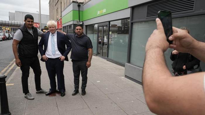 1241751505 BLACKPOOL, ENGLAND - JULY 07: Locals pose with a waxwork of Boris Johnson in front of a job centre on July 7, 2022 in Blackpool, England. Shortly after news broke that the prime minister would resign, Madame Tussauds Blackpool brought its waxwork of the prime minister to Blackpool's Jobcentre Plus. (Photo by Christopher Furlong/Getty Images)