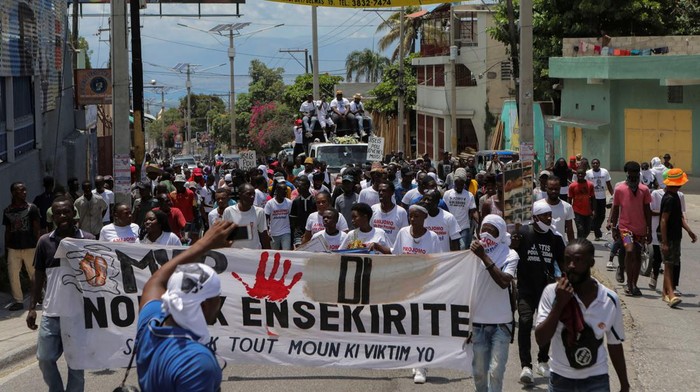 Aksi Ricuh Warnai Peringatan Satu Tahun Pembunuhan Presiden Haiti Moise A police officer holding a gun confronts a demonstrator over setting a roadblock with a tire during a protest to demand justice for President Jovenel Moise a year after his assassination, in Port-au-Prince, Haiti July 7, 2022. REUTERS/Ralph Tedy Erol TPX IMAGES OF THE DAY