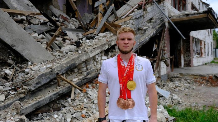 CHERNIHIV, UKRAINE - JULY 04: Ukrainian paralimpic athlete Dmytro Suyarko, who sold his bronze medal for 5,300 USD he won at the Paralimpic Olympics to donate the Ukrainian army, poses for a photo with his medals in front of the debris of his once training school in Chernihiv, Ukraine on July 04, 2022. (Photo by Abdullah Unver/Anadolu Agency via Getty Images)