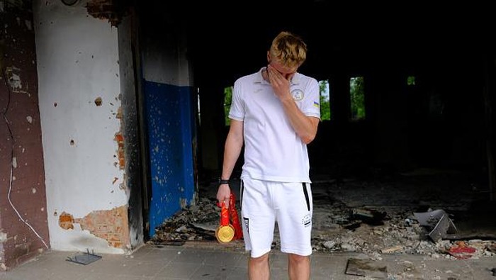 CHERNIHIV, UKRAINE - JULY 04: Ukrainian paralimpic athlete Dmytro Suyarko, who sold his bronze medal for 5,300 USD he won at the Paralimpic Olympics to donate the Ukrainian army, poses for a photo with his medals in front of the debris of his once training school in Chernihiv, Ukraine on July 04, 2022. (Photo by Abdullah Unver/Anadolu Agency via Getty Images)