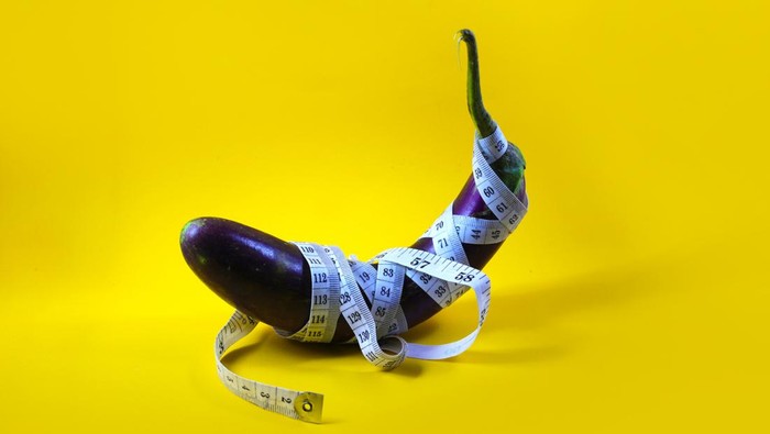 deformitas terong Close-up view of Purple eggplant wrapped with white measuring tape isolated on a yellow background. Concept of an increasing penis in men, viagra