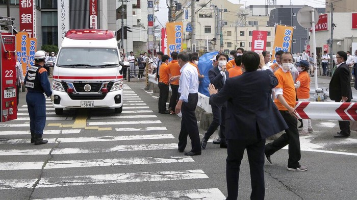 Japan’s former Prime Minister Shinzo Abe, center, falls on the ground in Nara, western Japan Friday, July 8, 2022. Abe was in heart failure after apparently being shot during a campaign speech Friday in western Japan, NHK public television said Friday. (Kyodo News via AP)