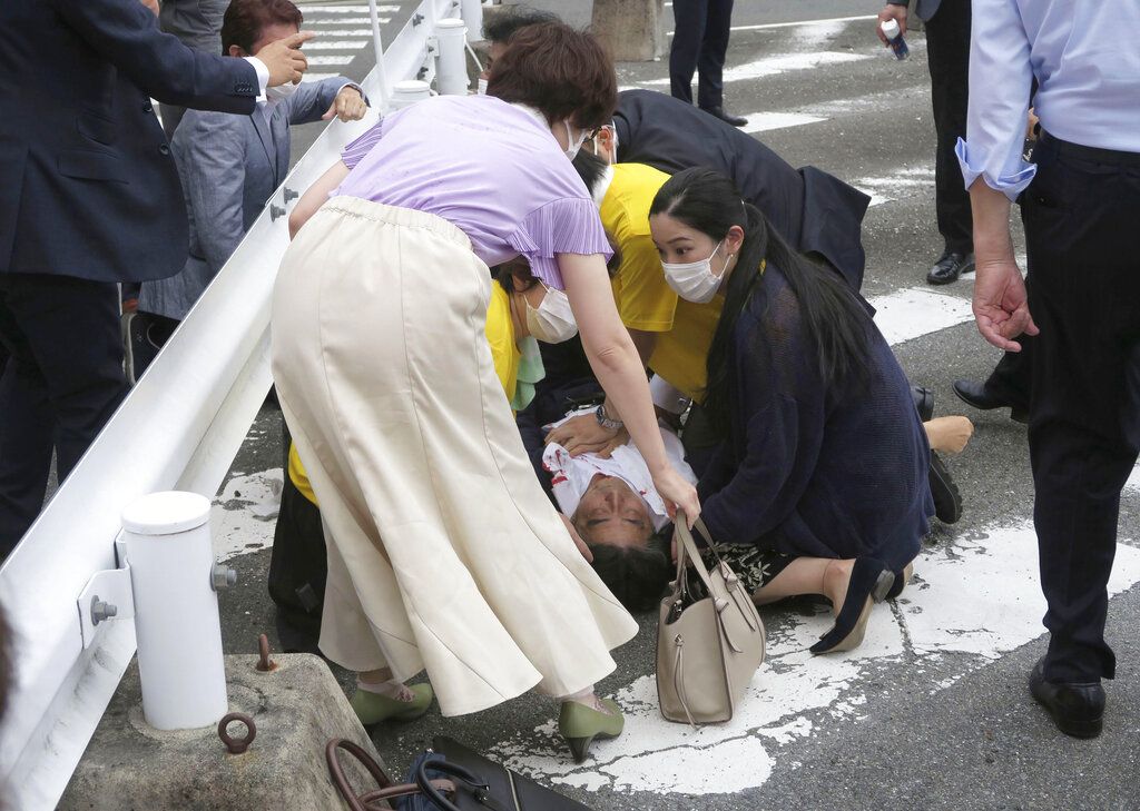 Japan's former Prime Minister Shinzo Abe, center, falls on the ground in Nara, western Japan Friday, July 8, 2022. Abe was in heart failure after apparently being shot during a campaign speech Friday in western Japan, NHK public television said Friday. (Kyodo News via AP)