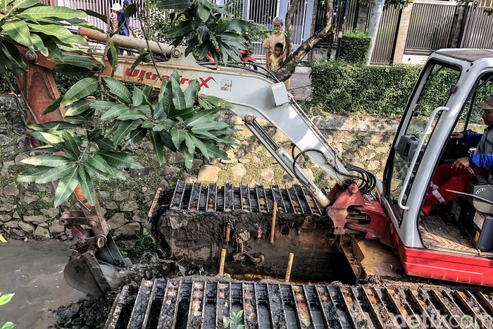 Mencegah Pendangkalan Aliran Sungai di Perumahan Petugas mengoperasikan alat berat mengeruk lumpur di anak sungai yang melintas di RW 09, Pondok Karya, Tangerang Selatan. Memastikan anak sungai mampu menampung debit air di saat hujan deras.